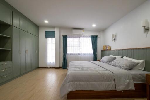 Spacious bedroom with green cabinets and large window