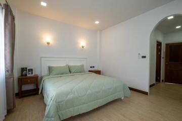 Cozy bedroom with green bedding, nightstands, and soft lighting