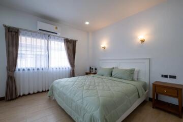 modern bedroom with double bed, nightstands, wall lamps, air conditioner, and large window with curtains