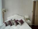 Modern Bedroom with White and Purple Pillows, Painted Wall, Hat Stand, and Partial Kitchen View