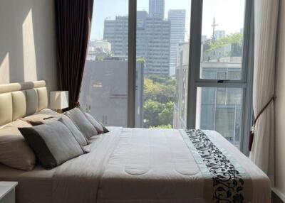 A well-lit bedroom with a large window offering city views