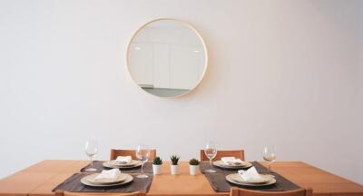 Dining room with a wooden table set for four, wall mirror, and small plants