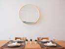 Dining room with a wooden table set for four, wall mirror, and small plants