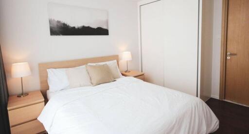 Modern bedroom with wooden elements, white bedding, and built-in wardrobe