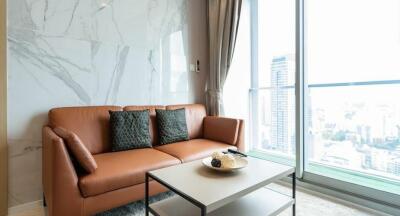 Modern living room with brown sofa and coffee table, large windows with city view