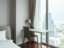 Bedroom with city view, desk, and large windows.