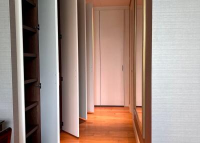 A spacious hallway with wooden flooring, multiple doors, and built-in shelves
