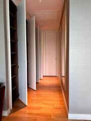 A spacious hallway with wooden flooring, multiple doors, and built-in shelves