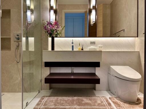 Modern bathroom with glass shower, vanity sink, and toilet