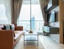 Modern living room with a city view, featuring a brown leather couch, wall-mounted TV, and a small coffee table.