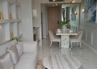 Modern living room with dining area, light-colored furniture, and wall decorations