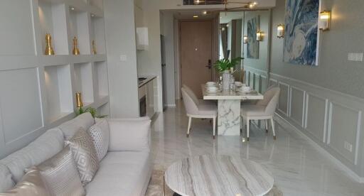 Modern living room with dining area, light-colored furniture, and wall decorations