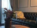 Living room with black leather sofa, plant and decorative pillows