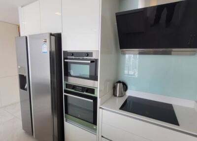 Modern kitchen with stainless steel refrigerator, built-in ovens, electric cooktop and black range hood