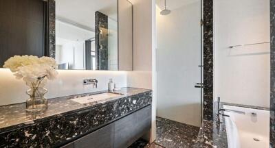 Modern bathroom with black marble countertops and glass shower