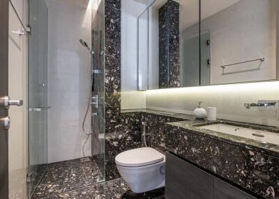 Modern bathroom with glass shower, black marble countertops, and wall-mounted sink