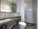 Modern bathroom with black marble countertop and glass shower door