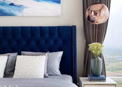 Modern bedroom with blue headboard, wall art, and nightstand
