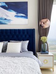 Modern bedroom with blue headboard, wall art, and nightstand