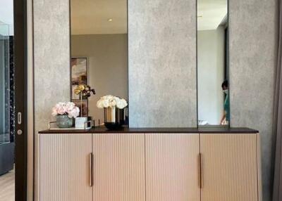 A bedroom with a wooden cabinet, decorative flowers, and mirrored panels