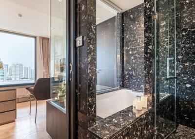 Modern bathroom with dark marble and an adjacent living area with large window