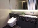 Modern bathroom with sleek black marble counter and toilet