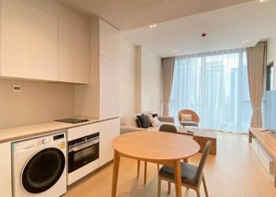 Open plan kitchen and living area with modern furnishings and large windows.