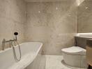 Modern bathroom with marble tiles, bathtub, and wall-mounted toilet