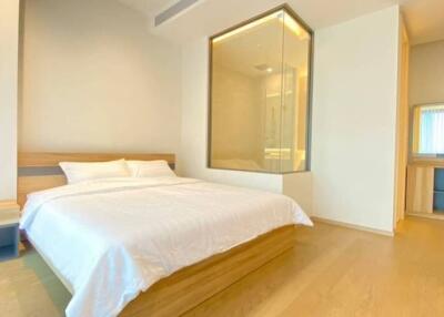 Bright and modern bedroom with a large bed, ensuite glass shower, and dressing area.