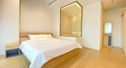 Bright and modern bedroom with a large bed, ensuite glass shower, and dressing area.