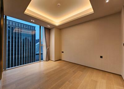 Empty modern living area with a large window, wooden flooring, and recessed lighting