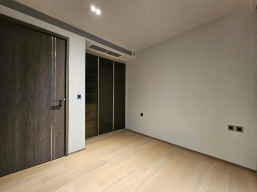 Empty bedroom with wooden flooring and a closet with sliding doors