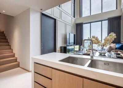 Modern kitchen and living area with large windows and stairway