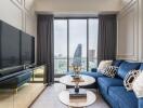 Modern living room with city view, blue couch, large TV, and coffee tables