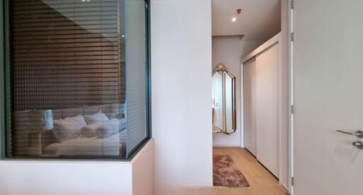 Bedroom view with a modern design featuring an internal window, bed, and a stylish hallway with a mirror.