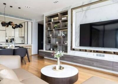 Modern living room with built-in shelving, wall-mounted TV, and open kitchen area