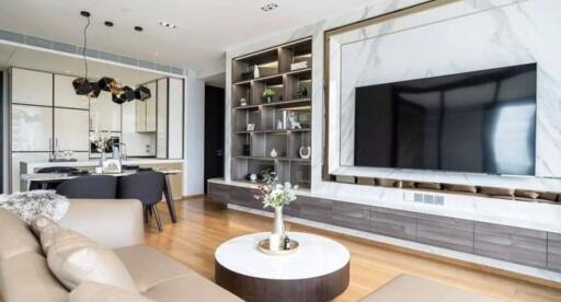 Modern living room with built-in shelving, wall-mounted TV, and open kitchen area