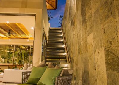Modern outdoor seating area with green cushioned chairs and staircase