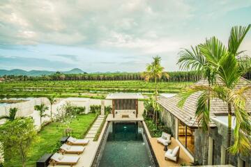 View of a swimming pool in the backyard of a house with lounge chairs, a garden, and scenic landscape