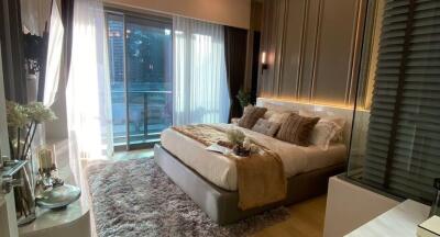 Modern bedroom with a large bed, plush rug, and access to a balcony.