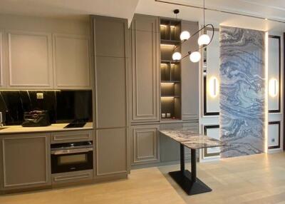 Modern kitchen with sleek cabinetry, built-in oven, and hanging lights.