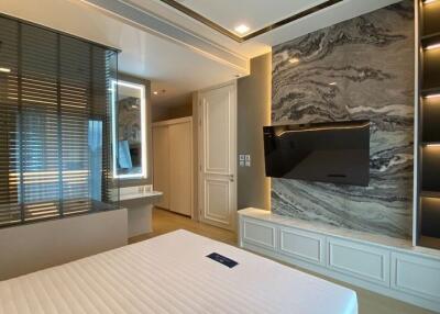 Modern bedroom with marble wall decor and mounted TV