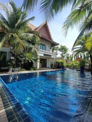 Exterior view of a house with a swimming pool surrounded by palm trees