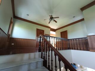 Staircase area with wooden handrails and ceiling fan