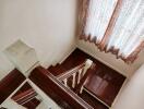 Interior view of a staircase with wooden steps and a curtain-covered window