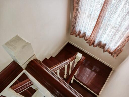 Interior view of a staircase with wooden steps and a curtain-covered window