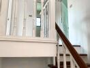 Well-lit staircase with wooden steps and white railing