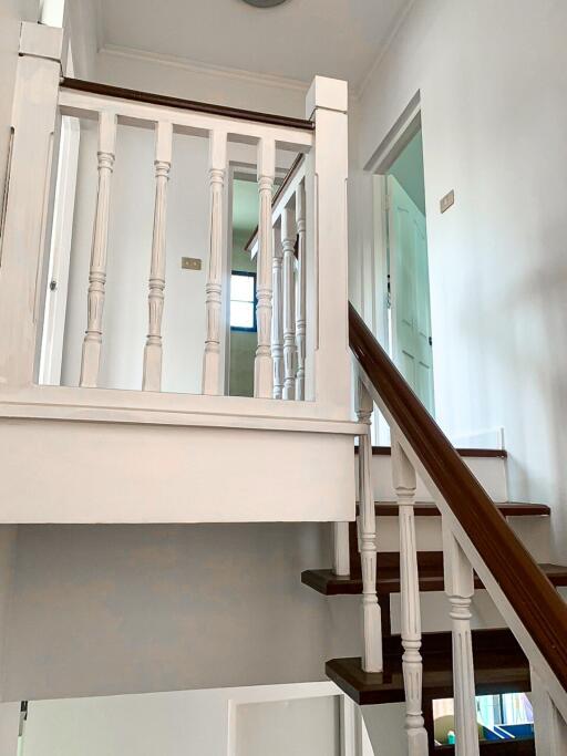 Well-lit staircase with wooden steps and white railing