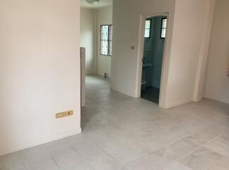 Interior view of a house with tiled floors, beige walls, and a view into a bathroom and another room