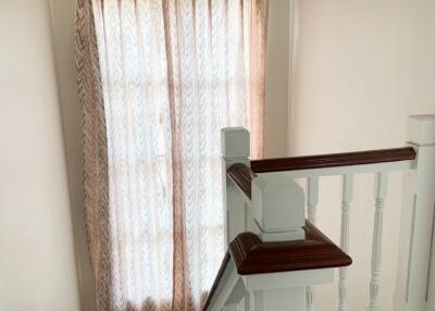 Staircase with wooden handrail and window with curtains